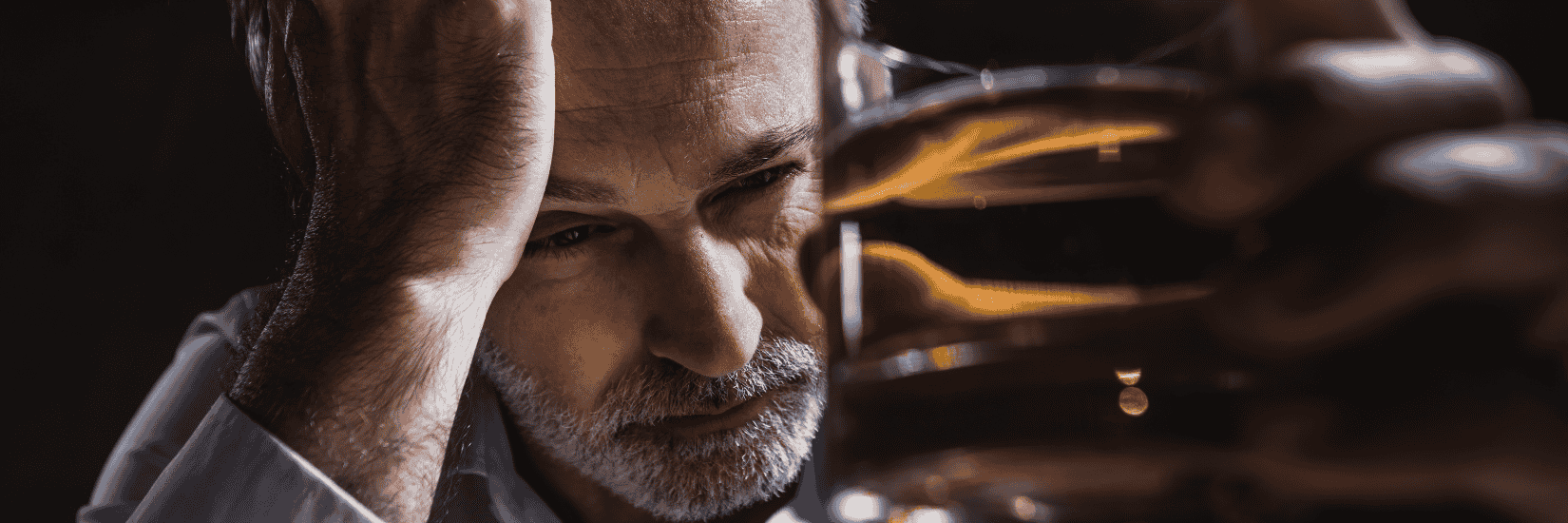 un homme regardant un verre d'alcool